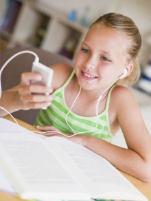 A student smiling as she listens through earphones while reading